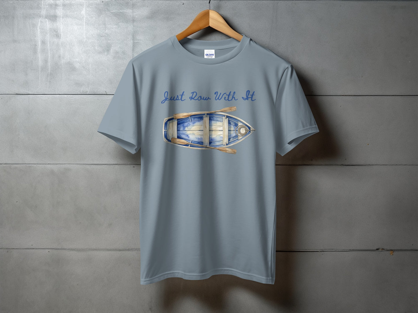 Blue t-shirt with a watercolor illustration of a rowboat and text "Just Row With It".