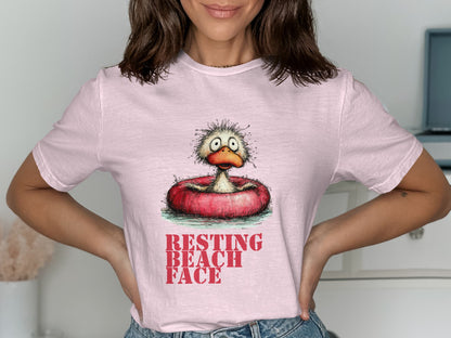 Pink t-shirt with cartoon duck in inner tube and "RESTING BEACH FACE" text.