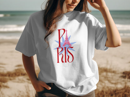White t-shirt with "PARIS" and Eiffel Tower graphic on a beach.