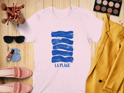 White t-shirt with blue wavy lines and "LA PLAGE" text, arranged with accessories.
