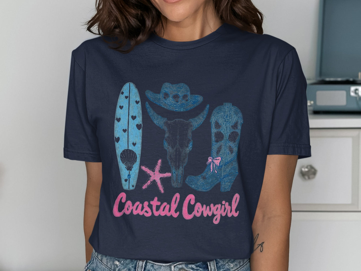 Coastal Cowgirl graphic tee with surfboard, bull skull, and cowboy boot.