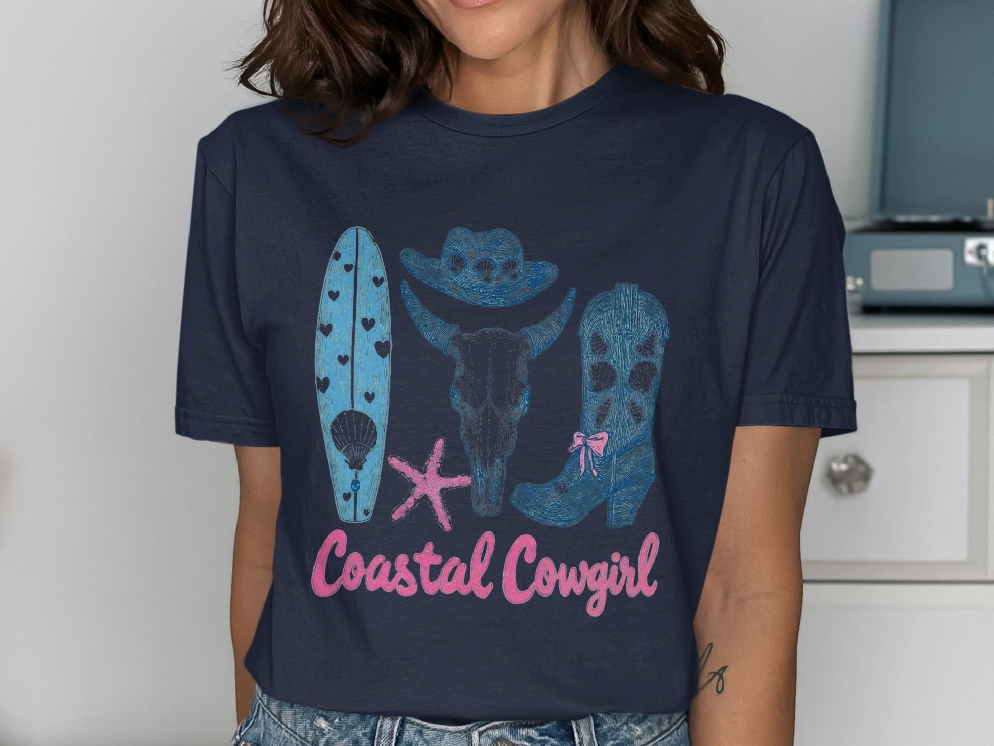 Coastal Cowgirl graphic tee with surfboard, bull skull, and cowboy boot.