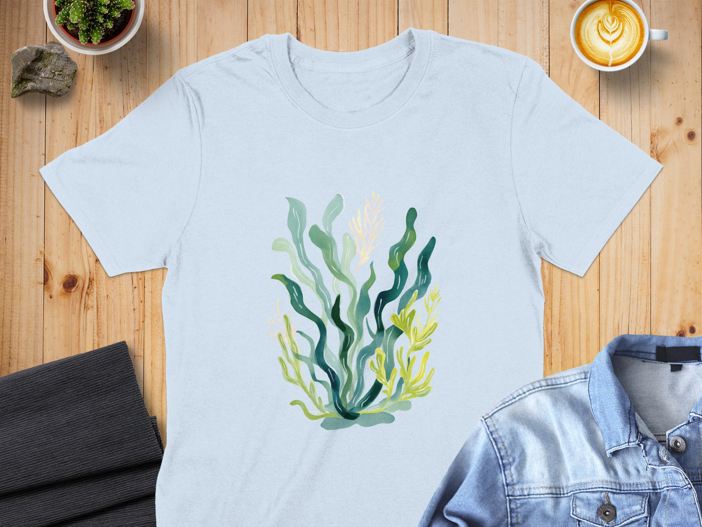 Light blue t-shirt with a watercolor illustration of green and yellow seaweed.
