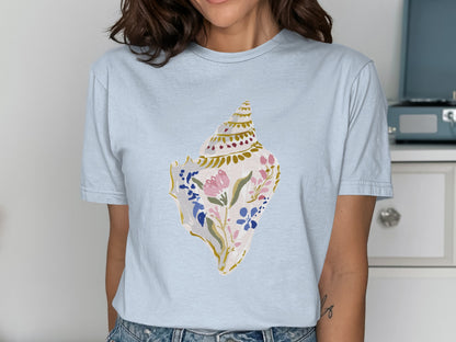 Light blue t-shirt featuring a detailed seashell illustration with pink and blue floral accents.