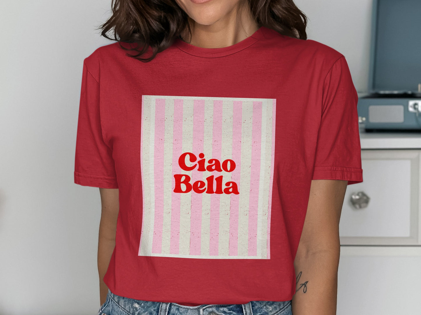 Red t-shirt with "Ciao Bella" in red lettering on a pink and white striped background.