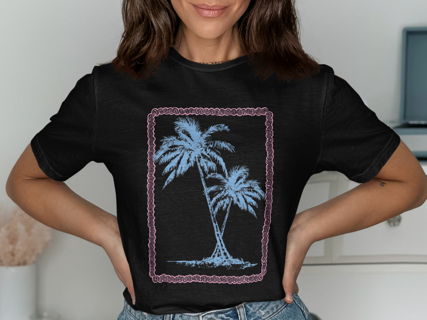 Black t-shirt with twin palm trees design within a pink border.
