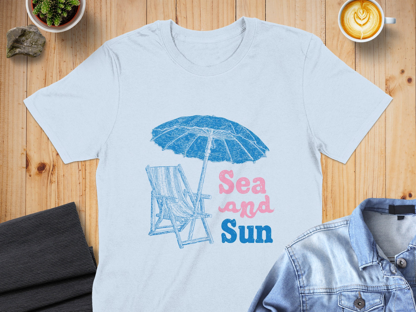 Light blue t-shirt with beach umbrella, chair, and "Sea and Sun" text.