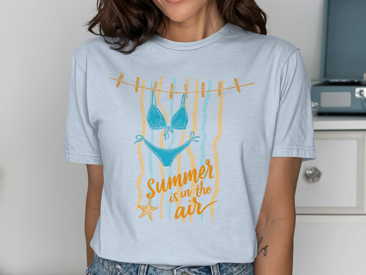 Blue bikini hanging on a clothesline with "Summer is in the air" text.