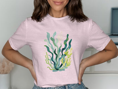 Pink t-shirt with a colorful illustration of seaweed and kelp.