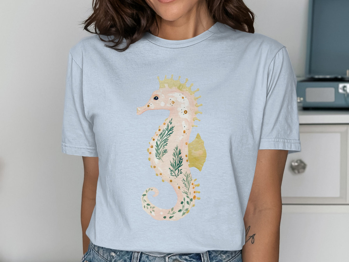 Light blue t-shirt with a watercolor seahorse illustration and crown.
