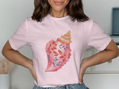 Pink t-shirt with a watercolor illustration of a seashell with floral details.