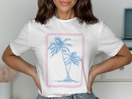 White t-shirt with a pastel pink border and distressed palm trees graphic.