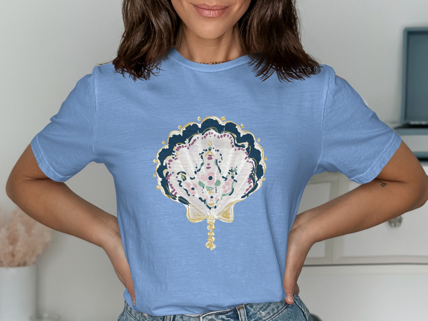Light blue t-shirt with a detailed seashell graphic in pastel colors.
