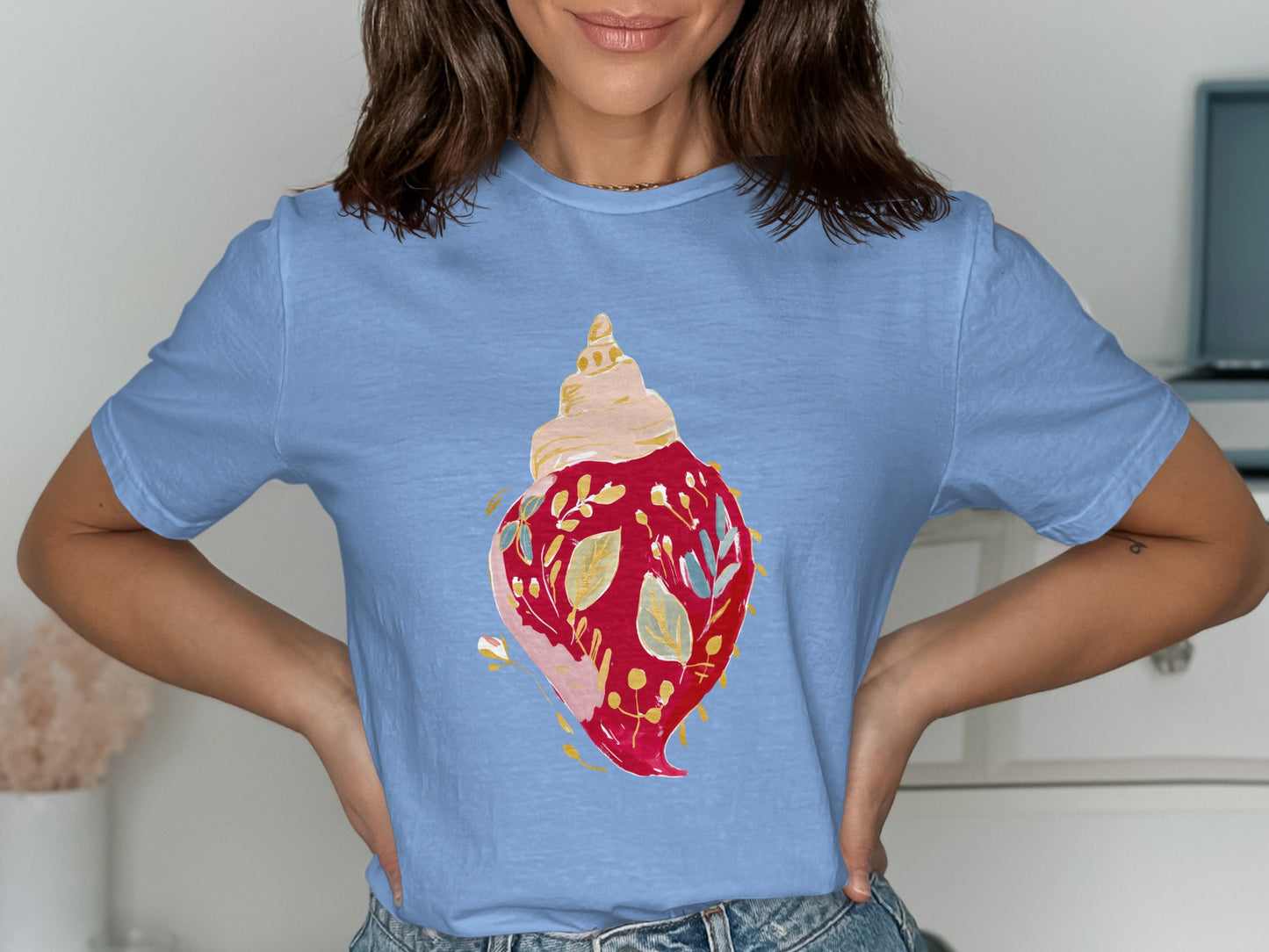 Blue t-shirt with a watercolor seashell illustration featuring red leaves and blue floral accents.
