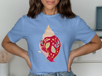 Blue t-shirt with a watercolor seashell illustration featuring red leaves and blue floral accents.