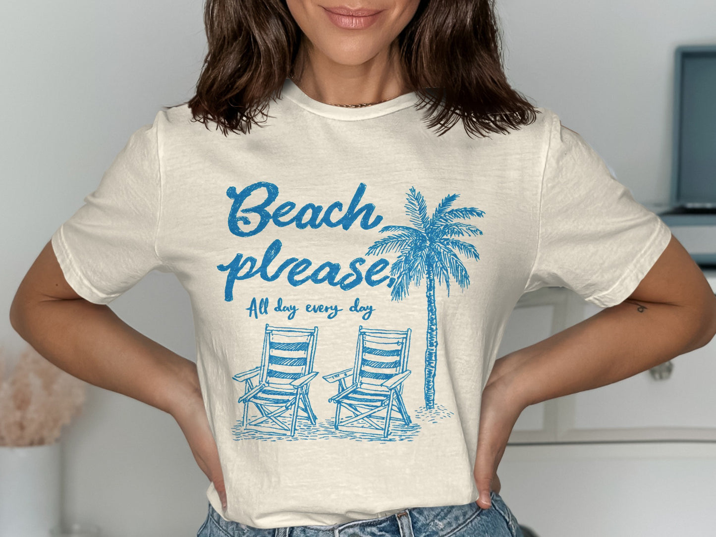 Cream t-shirt with "Beach please. All day every day" and palm tree and chairs.