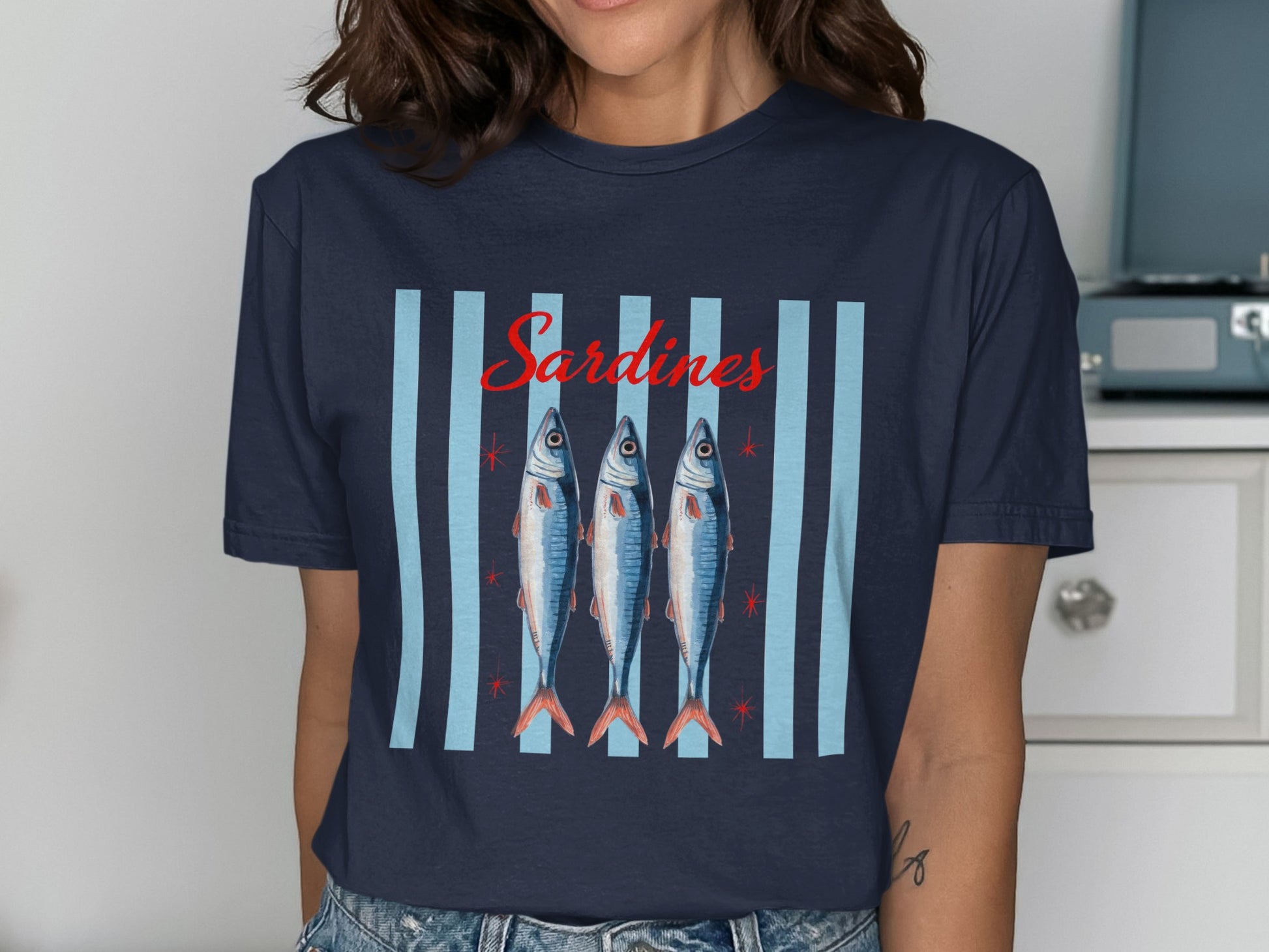 Navy t-shirt with three fish and "Sardines" text on a striped background.