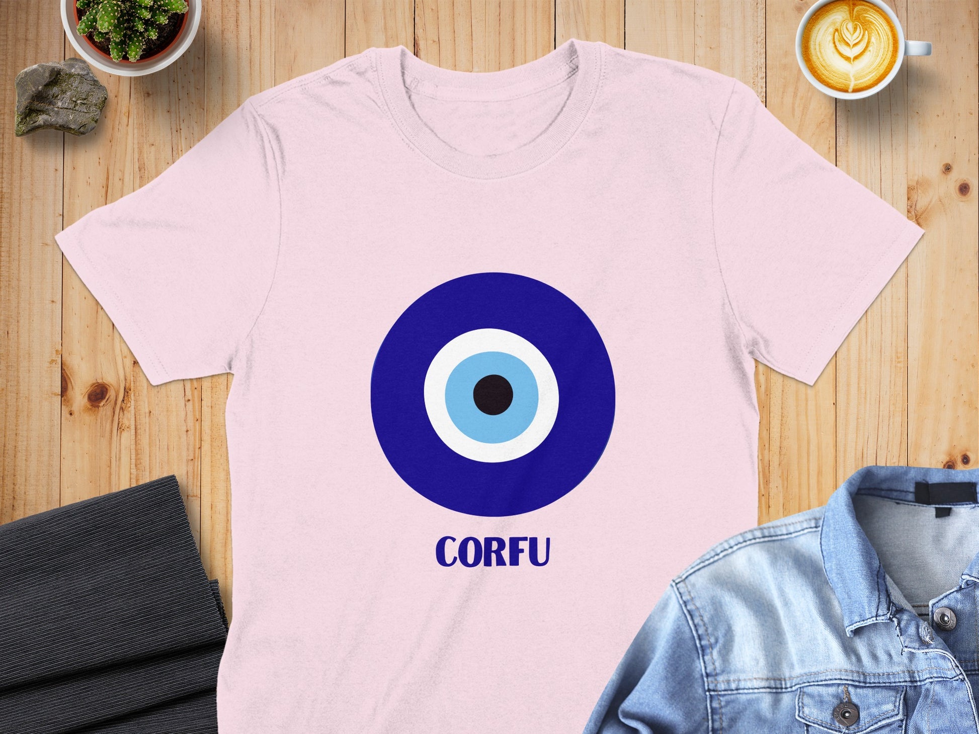 Pink t-shirt with a blue and white evil eye design and "CORFU" text.