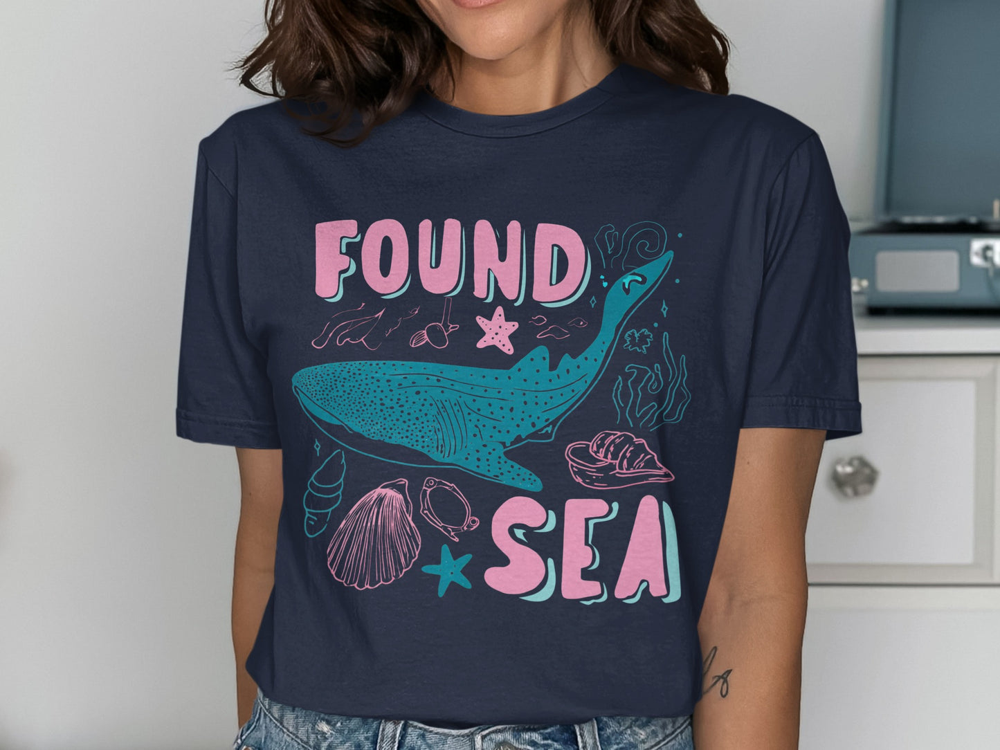 Dark blue t-shirt with whale, shells, and "FOUND SEA" text.