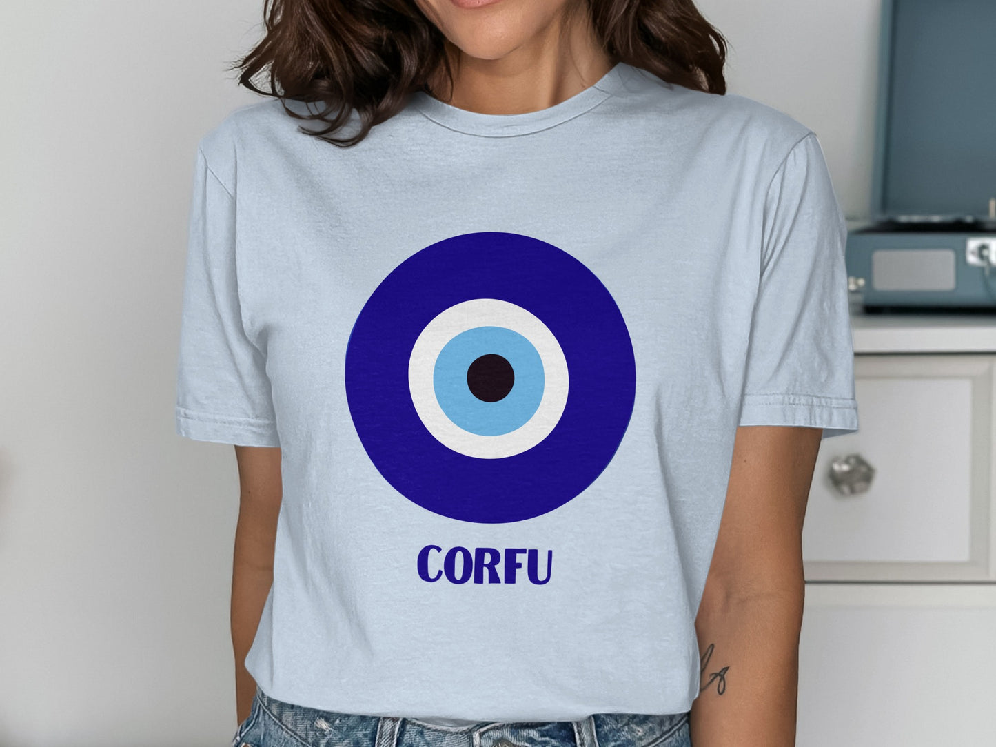 Light blue t-shirt with a blue and white evil eye symbol and "CORFU" text.
