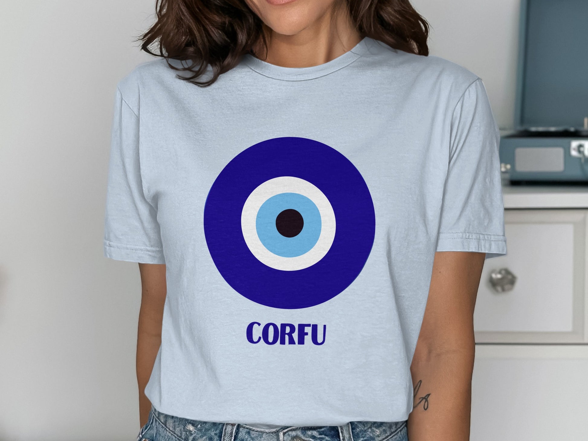 Light blue t-shirt with a blue and white evil eye symbol and "CORFU" text.