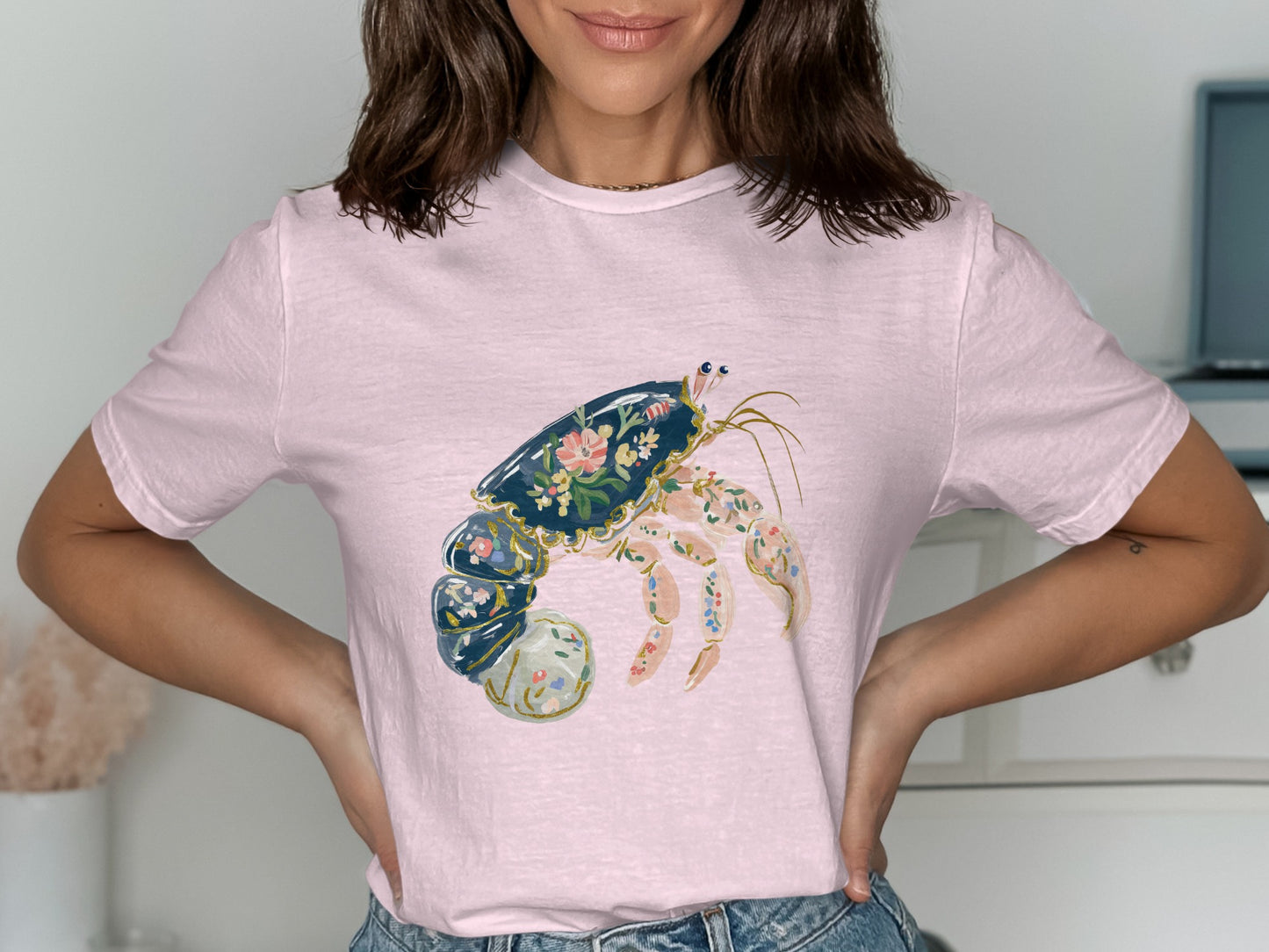 Light pink t-shirt featuring a detailed illustration of a hermit crab with floral patterns.
