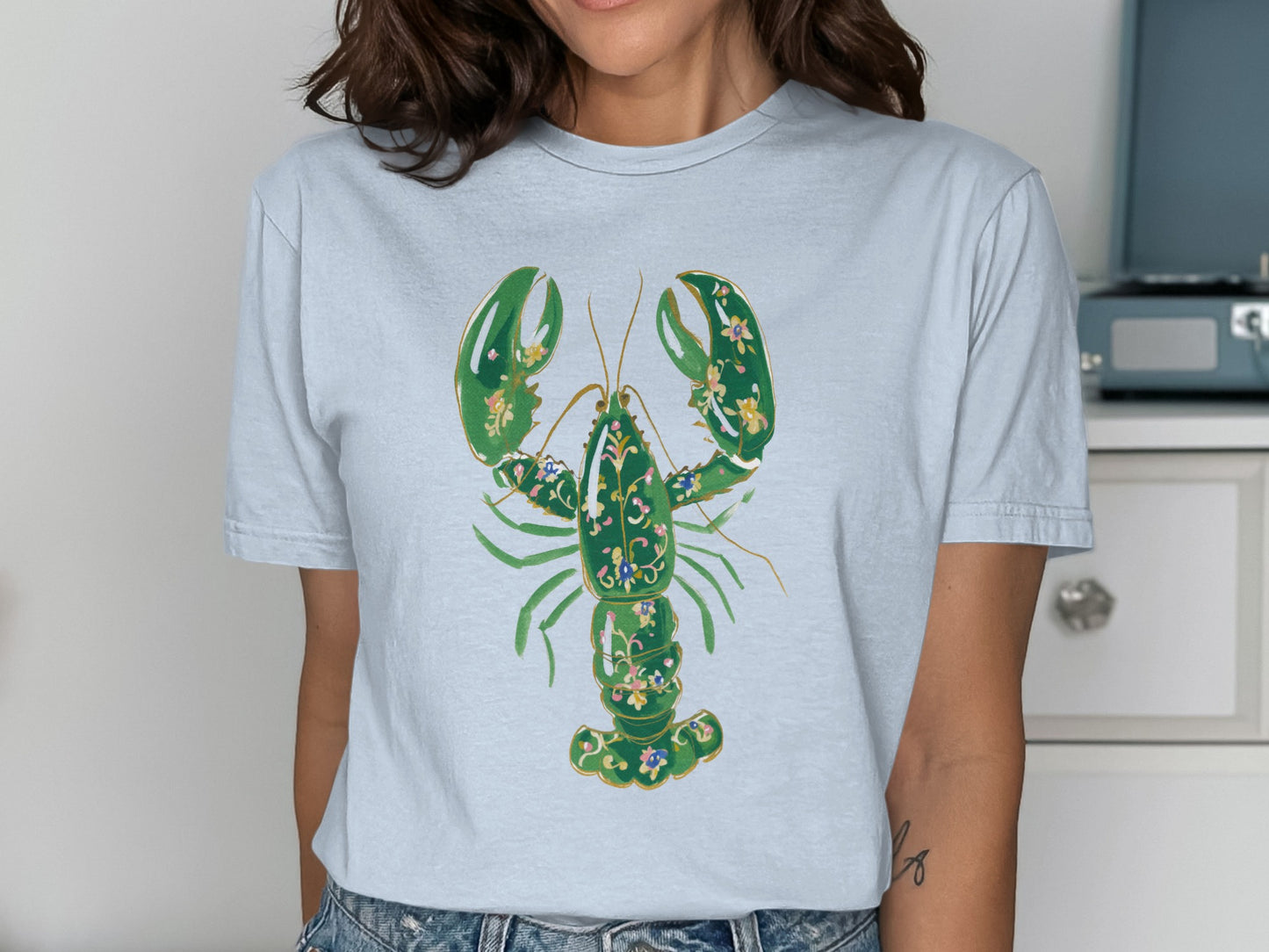 Light blue t-shirt with a green lobster graphic and floral accents.