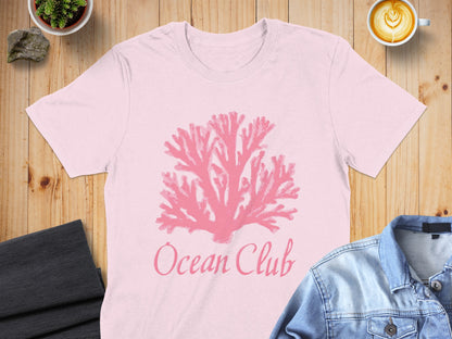 Pink coral graphic and "Ocean Club" text on a light pink t-shirt.