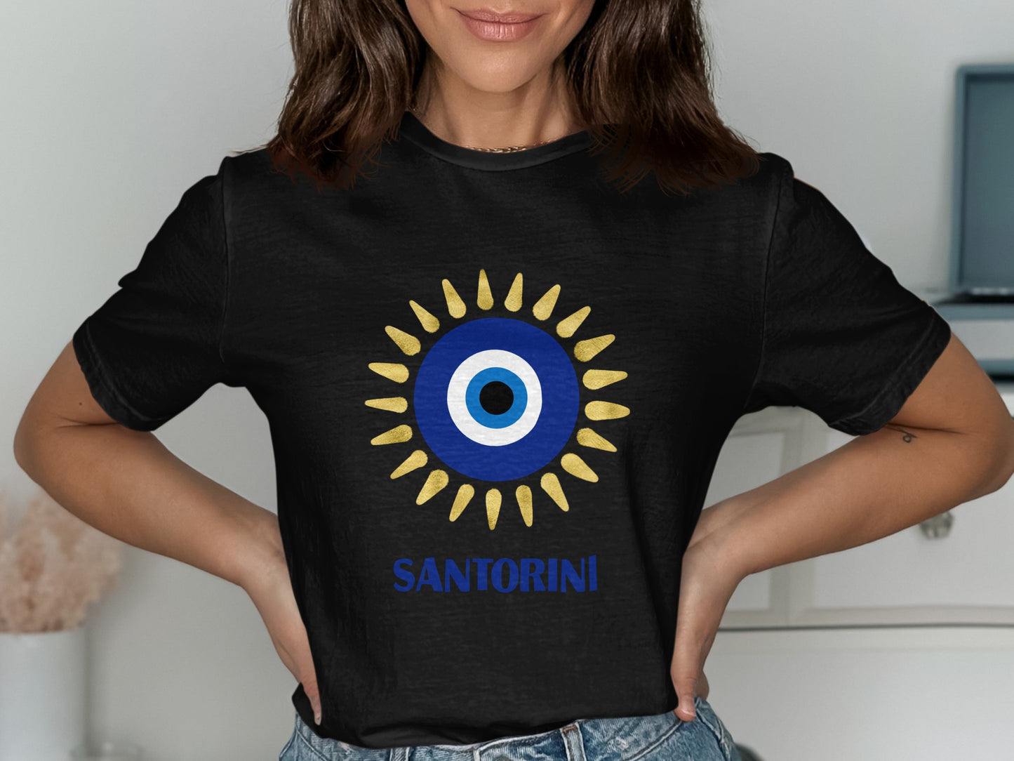 Black t-shirt with a blue and yellow evil eye design and "SANTORINI" text.
