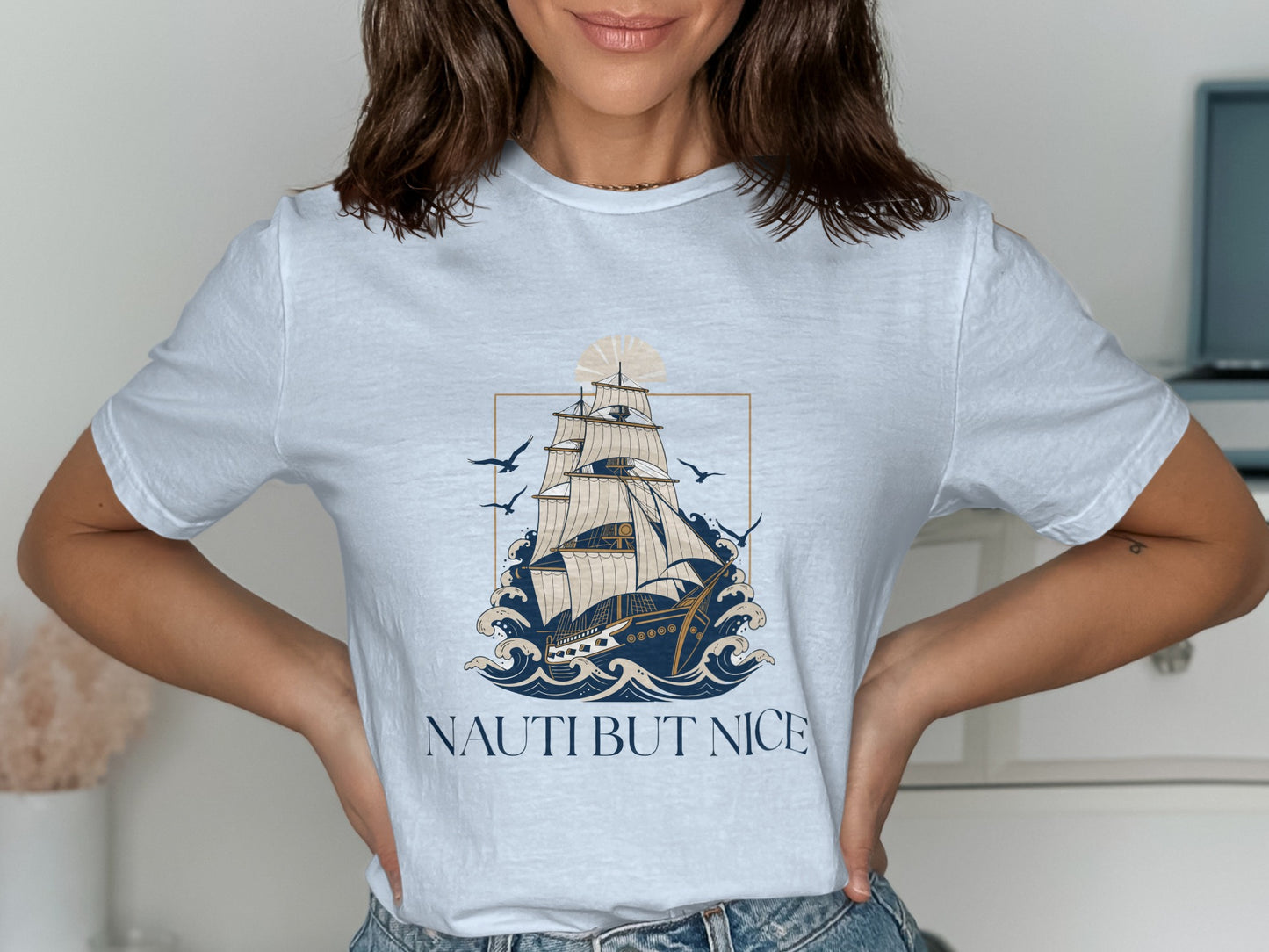White t-shirt with sailing ship, waves, and text "NAUTI BUT NICE".