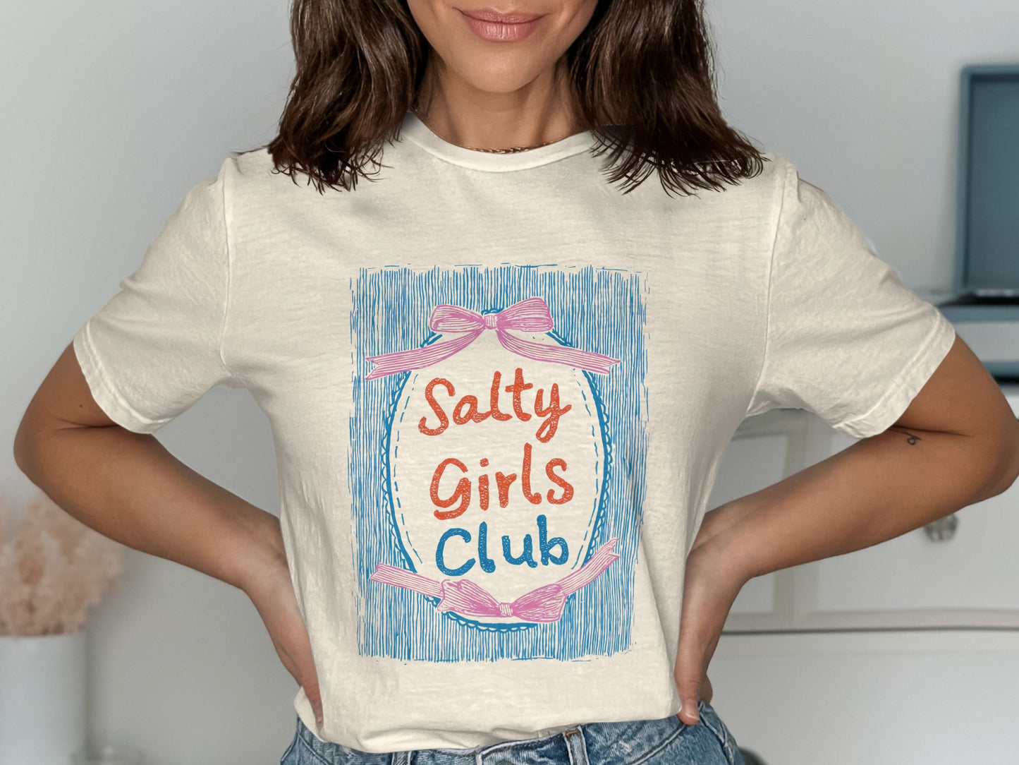 Cream t-shirt with "Salty Girls Club" text and pink ribbon graphic.