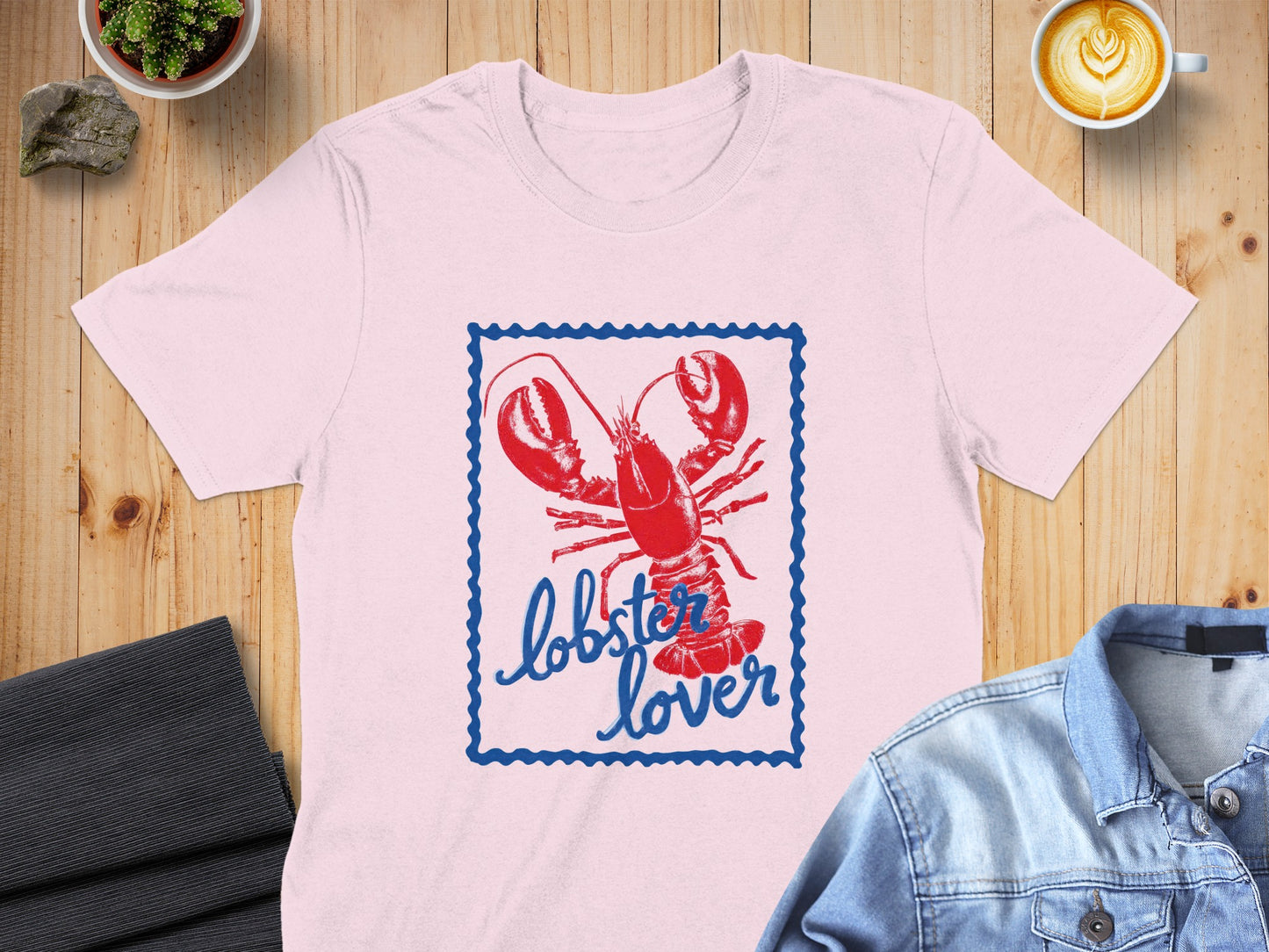 Pink t-shirt with a blue bordered stamp graphic of a red lobster and the text "lobster lover".