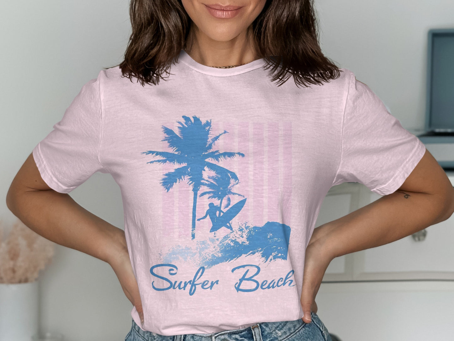 Pink t-shirt with blue surfer and palm tree graphic and text "Surfer Beach."