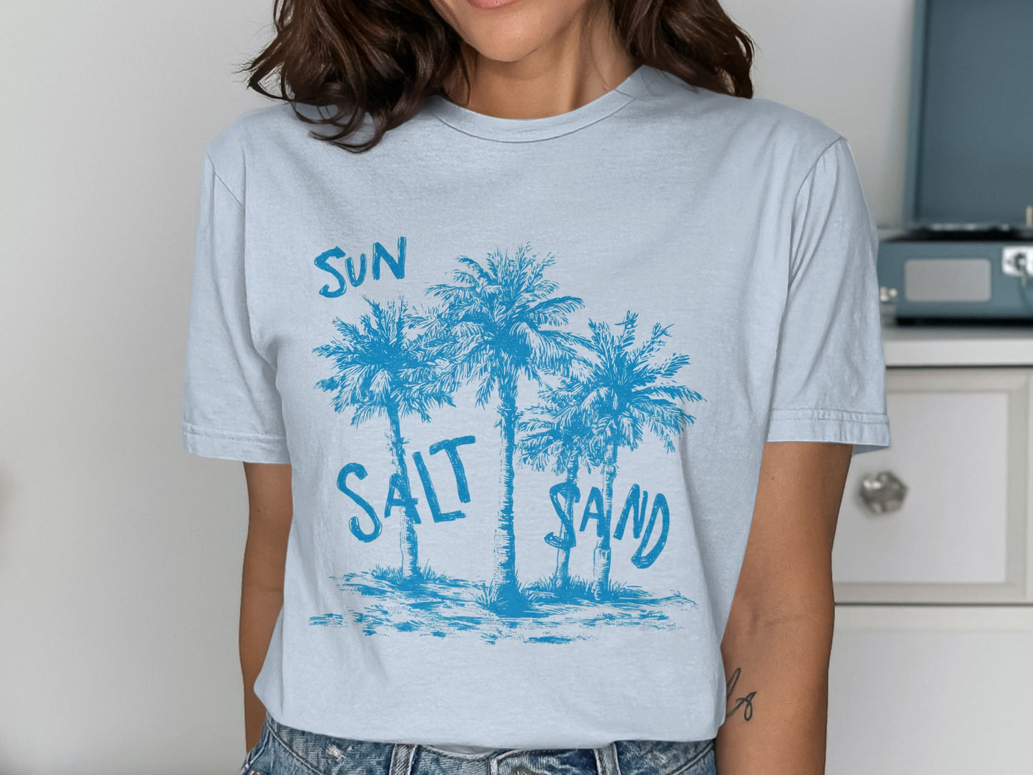 Light blue t-shirt with palm trees and "SUN SALT SAND" text.