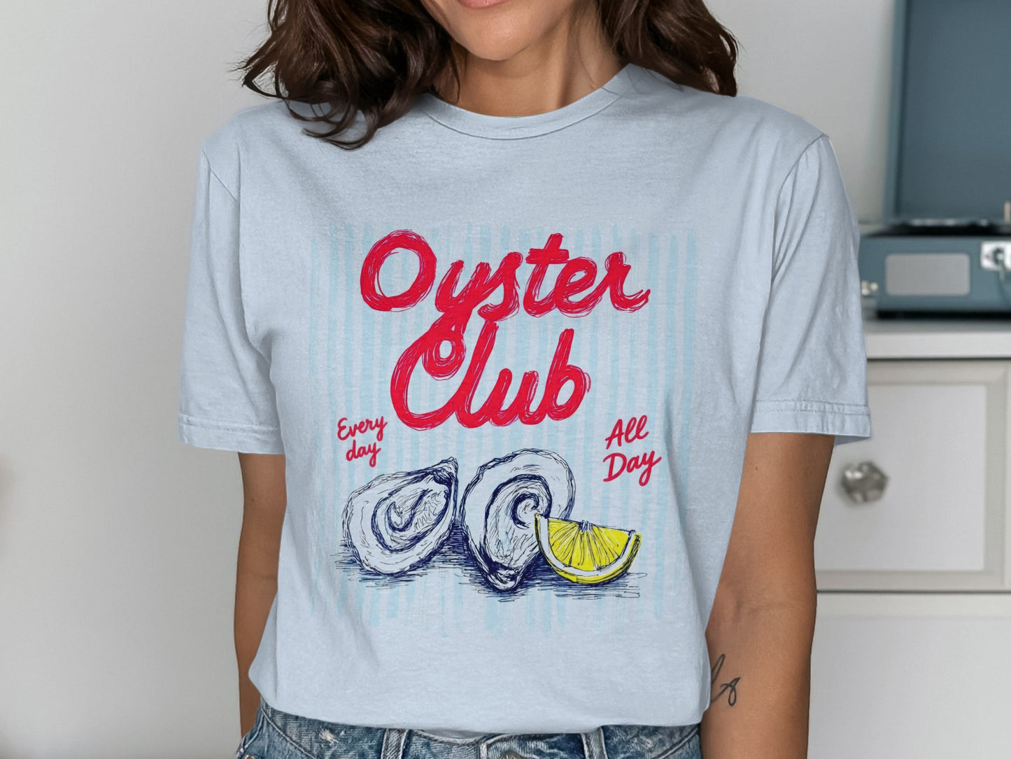 Oyster Club Every Day All Day graphic on a light blue striped t-shirt.