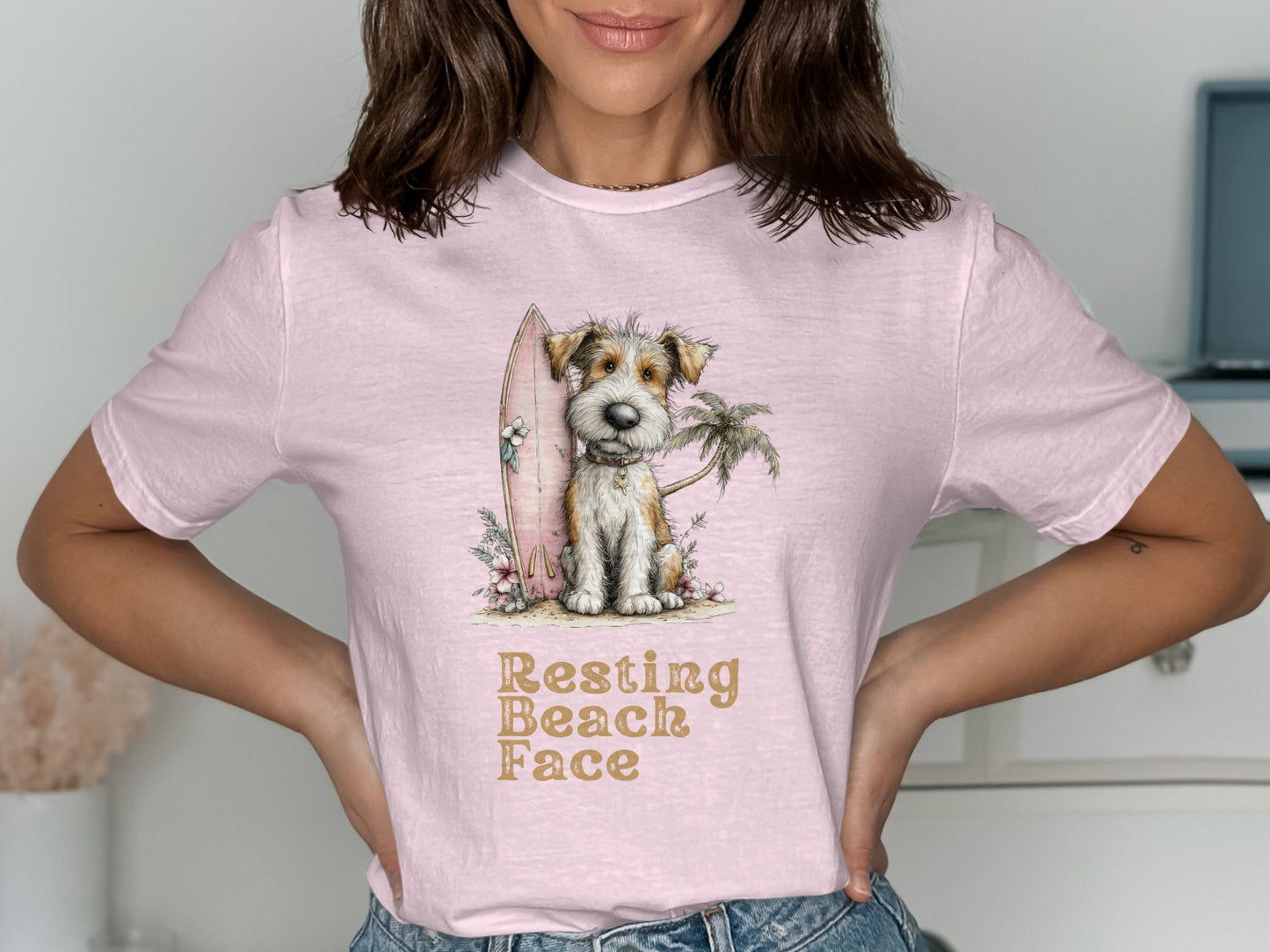 Pink t-shirt with a scruffy dog, surfboard, palm tree, and text "Resting Beach Face".