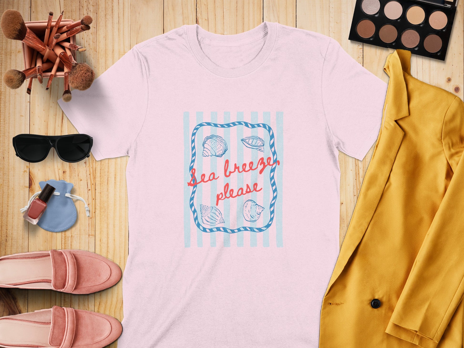 Pink t-shirt with "Sea breeze please" text and shells on a striped background.