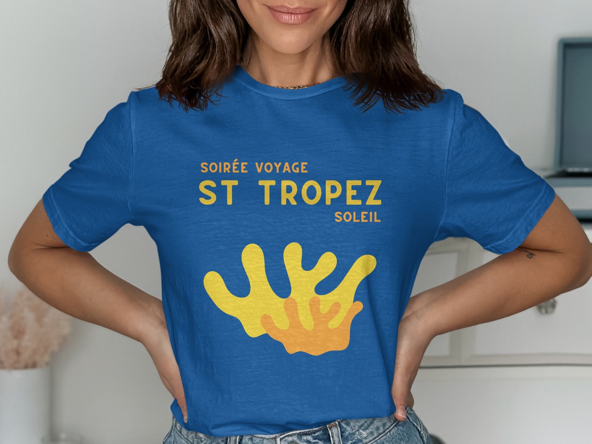 Blue t-shirt with "Soirée Voyage St Tropez Soleil" and abstract yellow graphic.