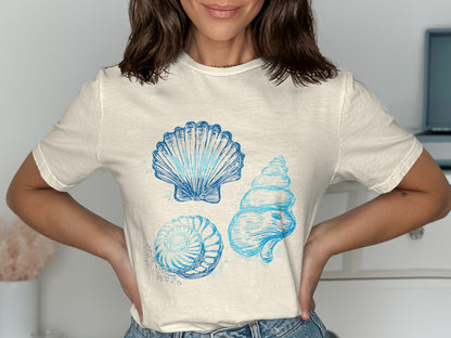 Cream t-shirt with three blue seashell illustrations.