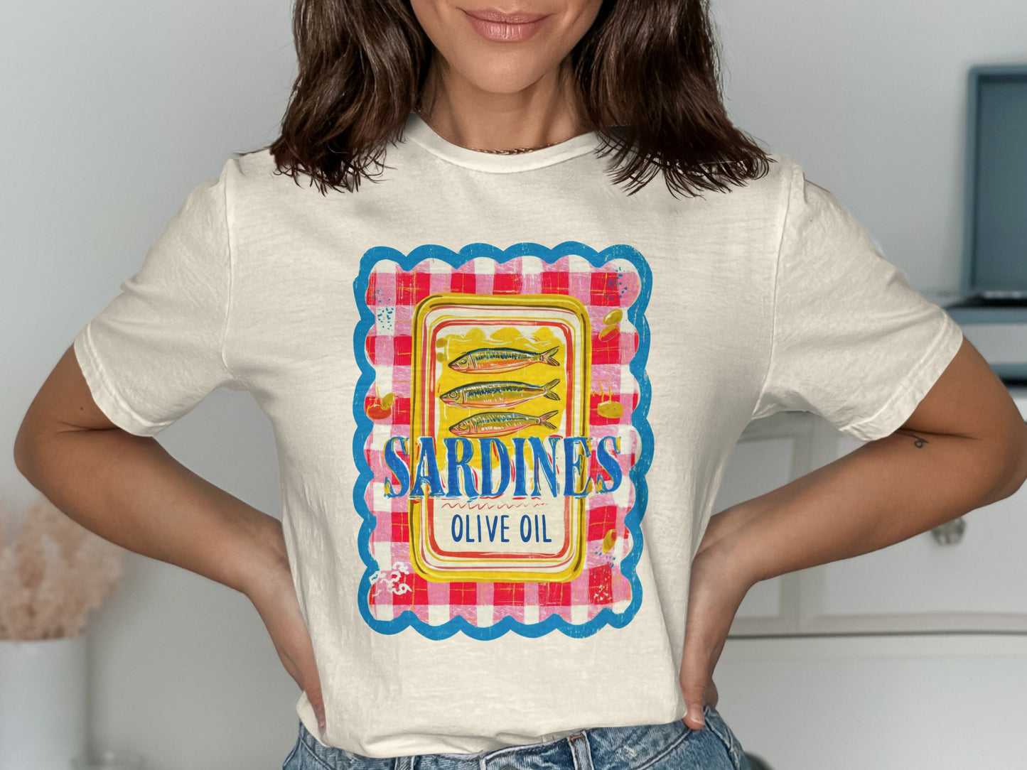 White t-shirt featuring a retro tin of sardines in olive oil graphic.