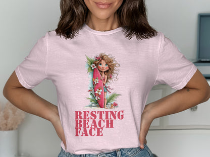 Pink t-shirt featuring a young woman with a surfboard and text "RESTING BEACH FACE".