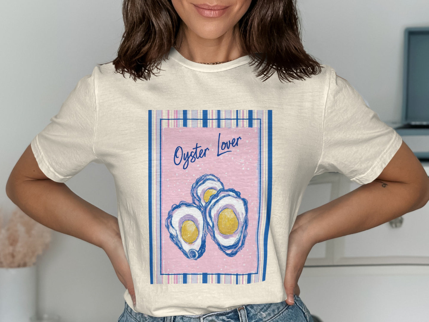 Cream t-shirt with "Oyster Lover" text and three stylized oysters on a pink background.