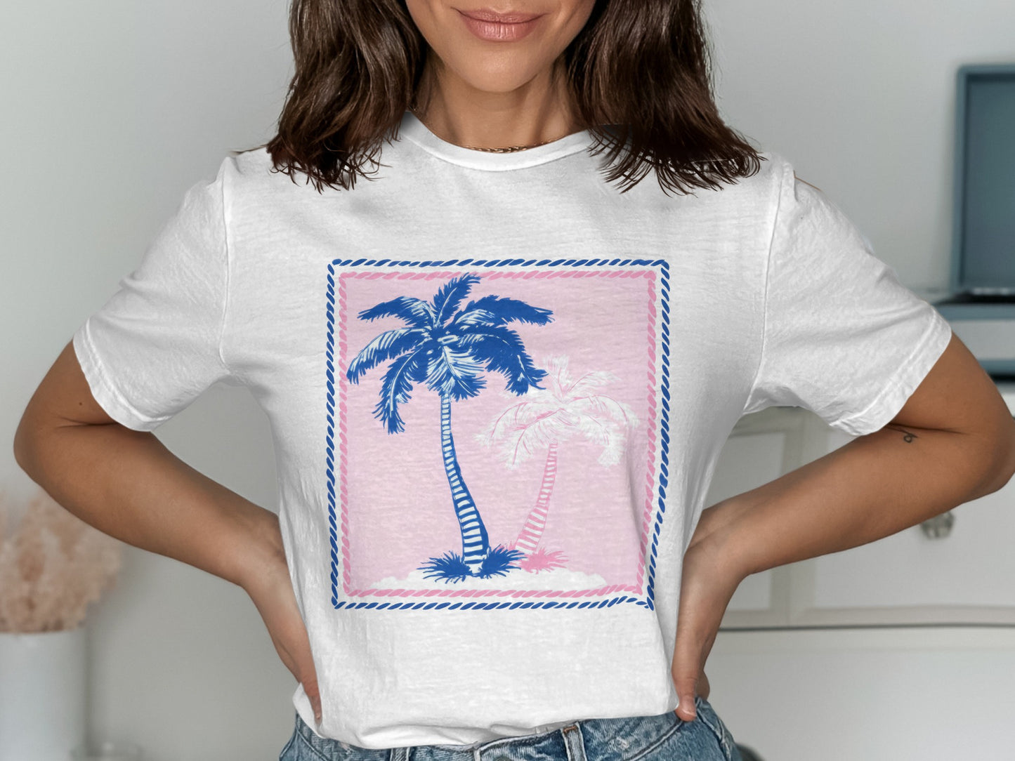 White t-shirt with pink and blue palm trees in a framed design.