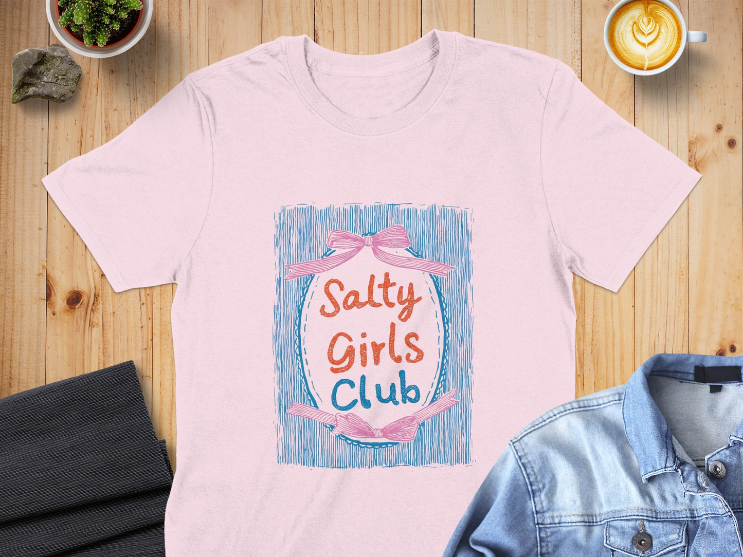 Pink t-shirt with "Salty Girls Club" text and blue ribbon design.