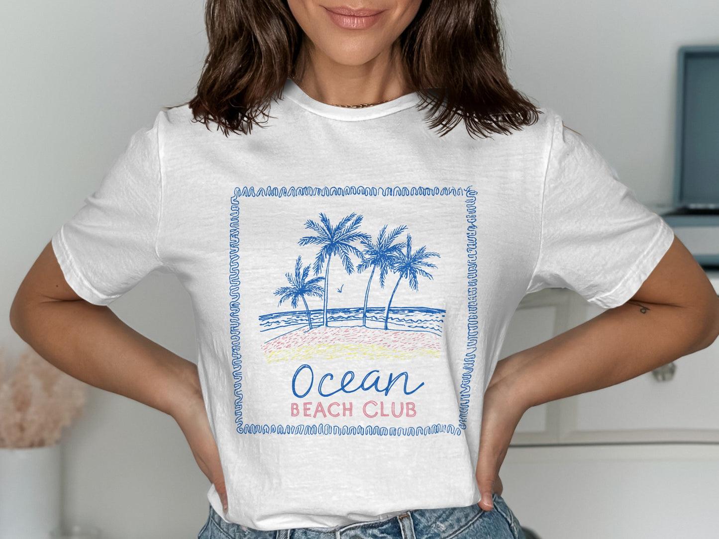 White t-shirt with blue and pink Ocean Beach Club palm tree graphic.