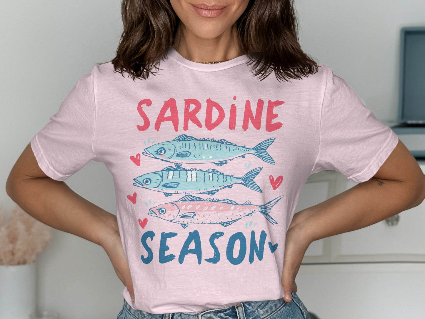 Pink t-shirt with three sardines and text "SARDINE SEASON" in blue.