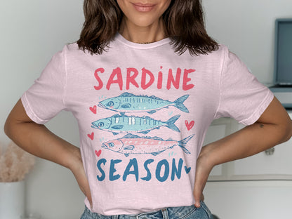 Pink t-shirt with three sardines and text "SARDINE SEASON" in blue.