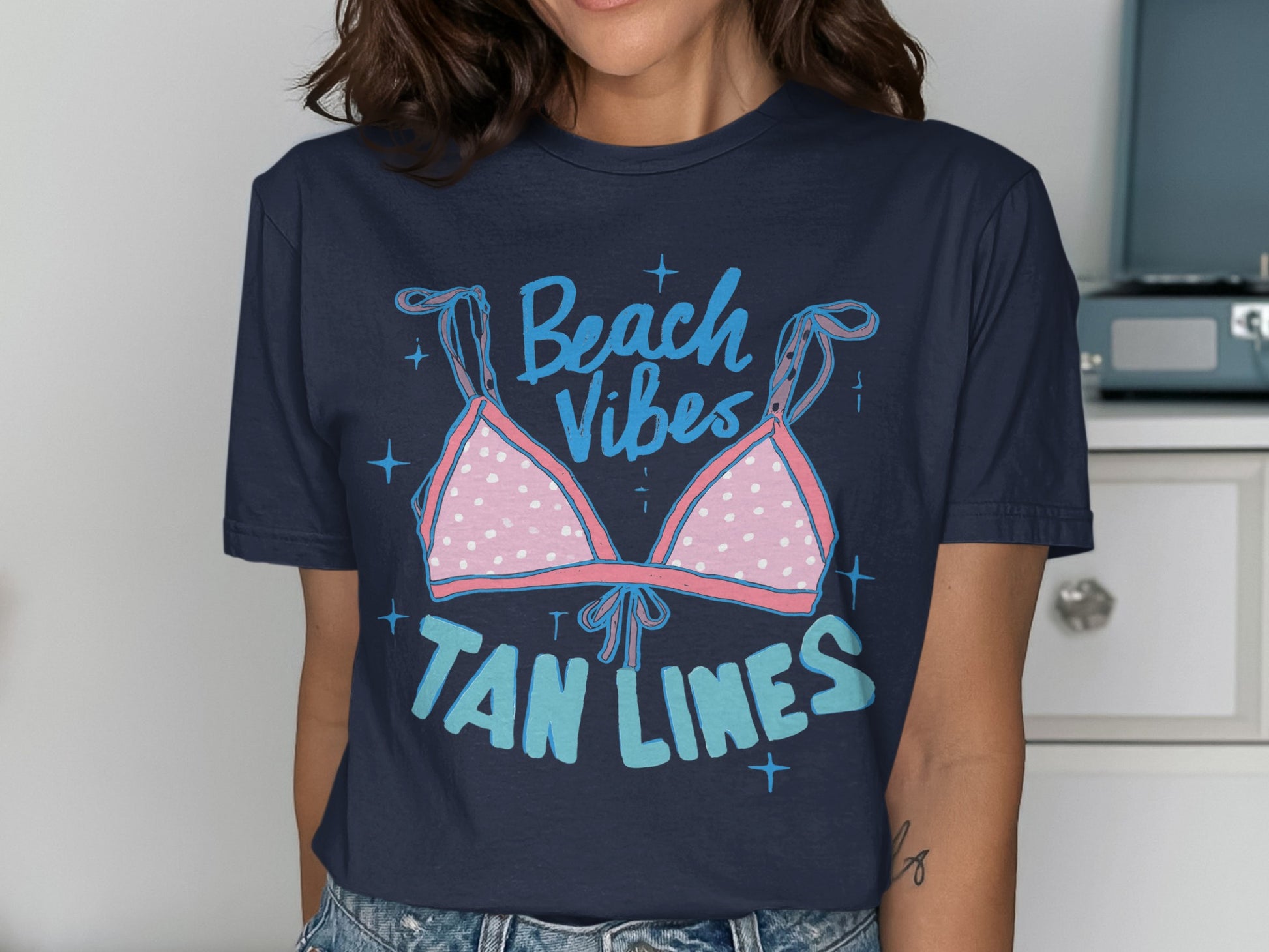 Navy t-shirt with pink polka dot bikini top and "Beach Vibes Tan Lines" text.