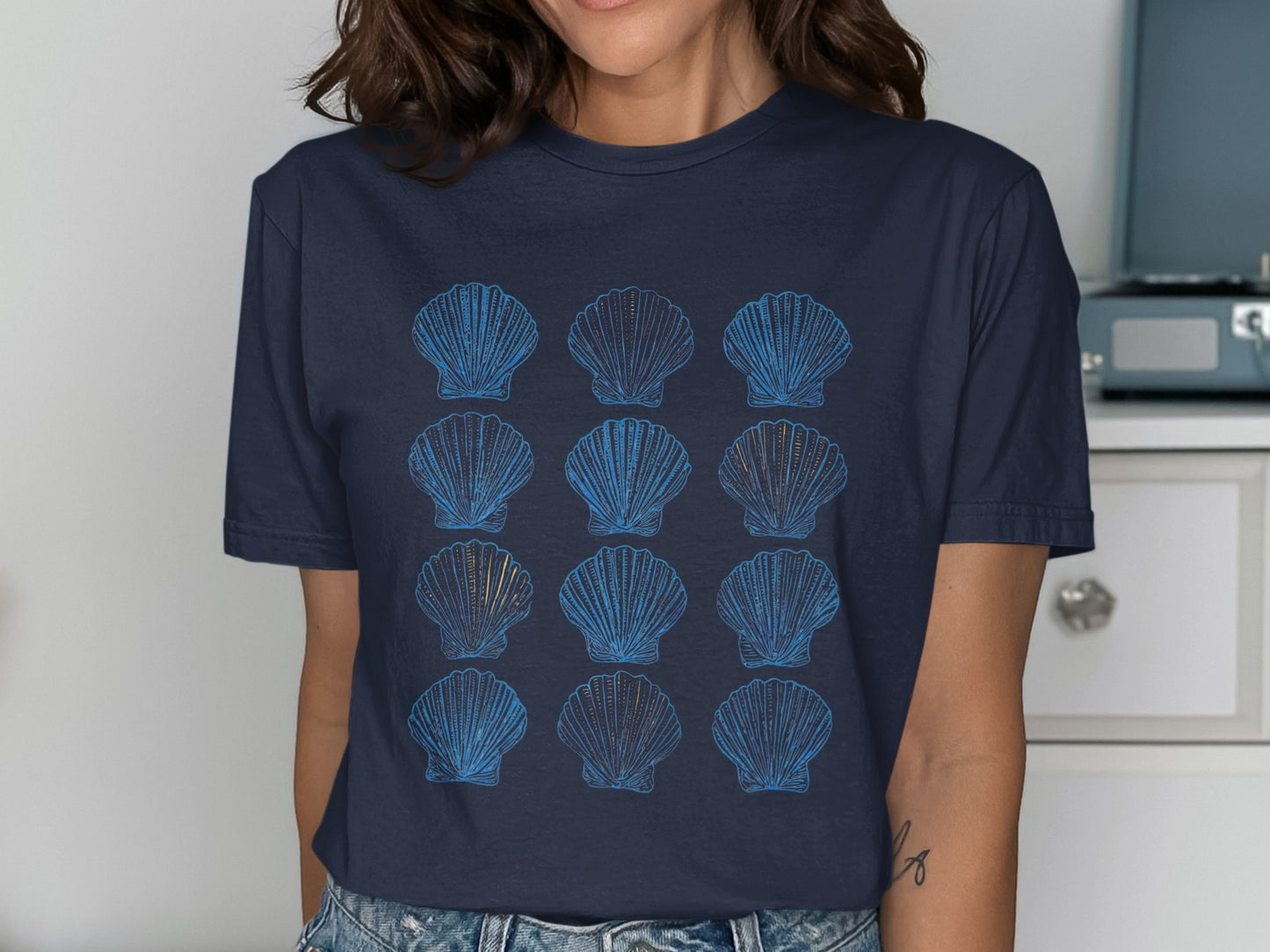Navy t-shirt with a grid of stylized blue and yellow scallop shells.