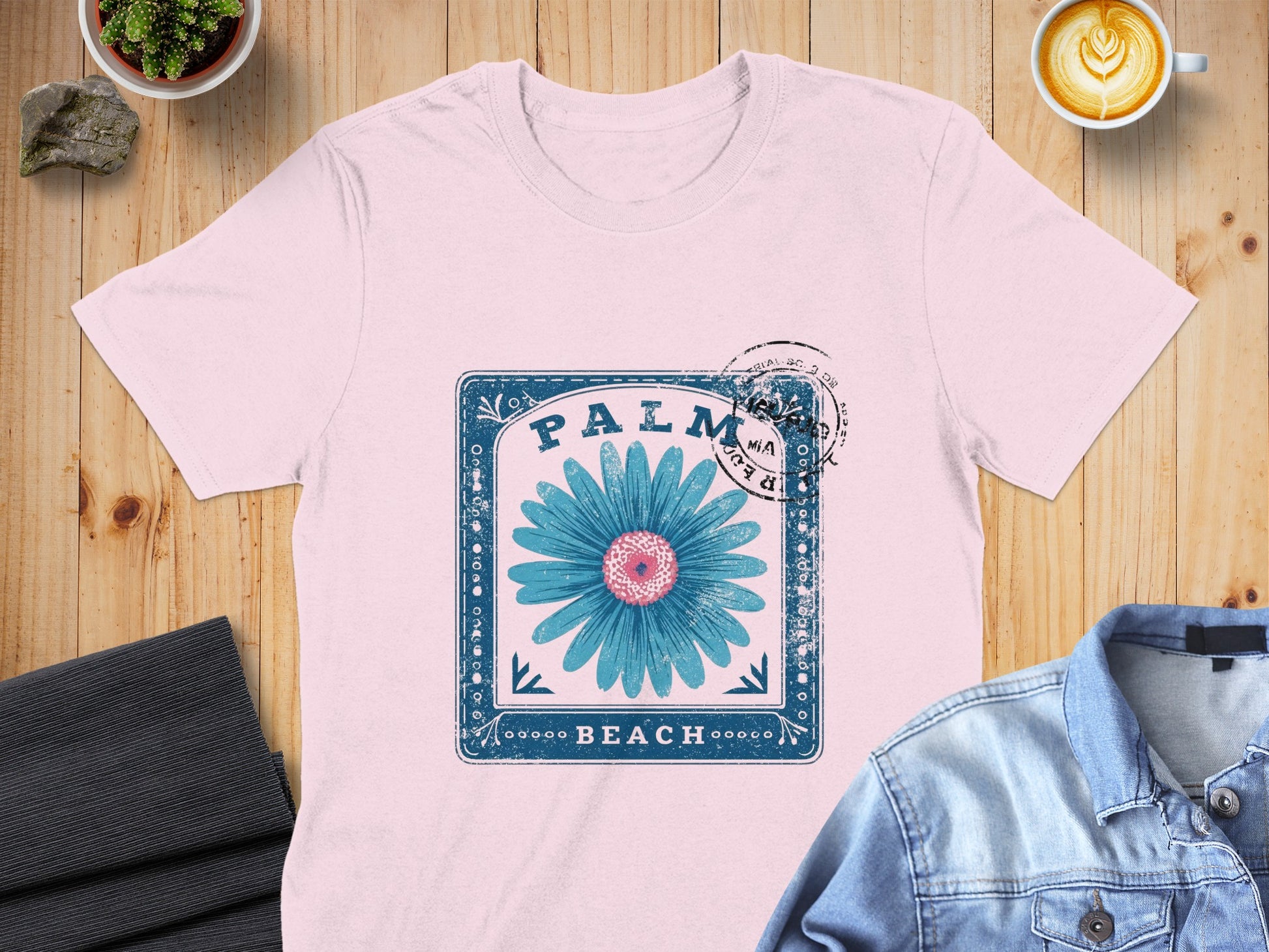Pink t-shirt with blue flower and "Palm Beach" text in vintage stamp design.